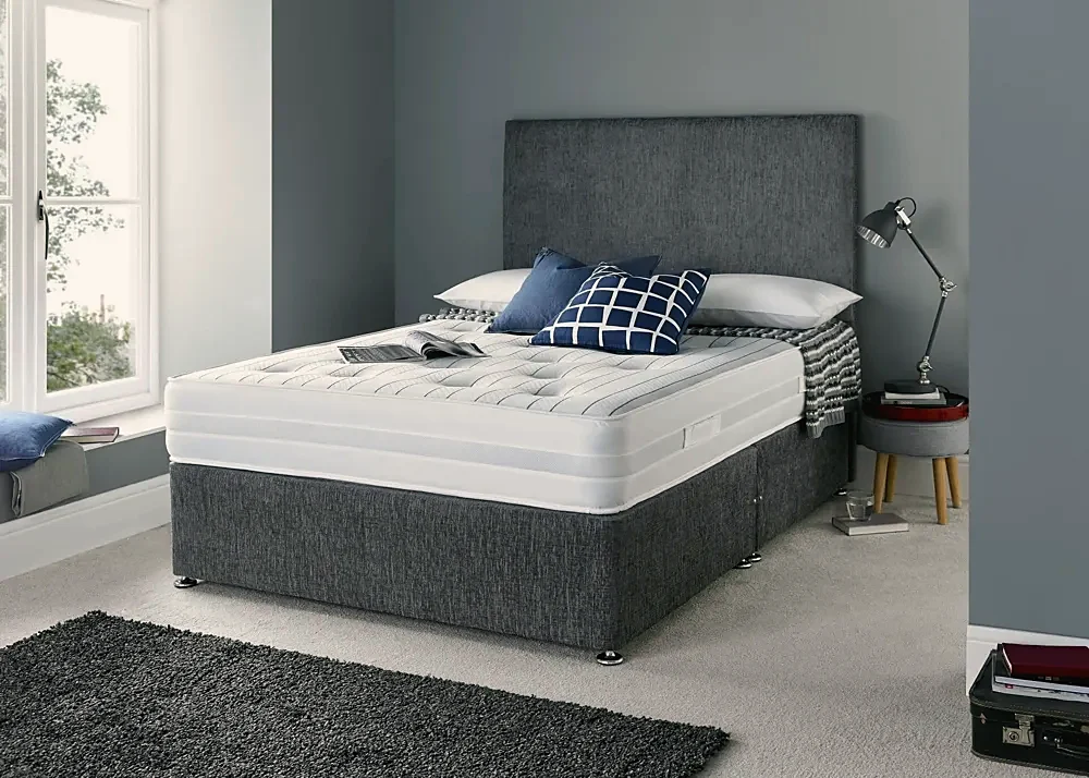 A grey divan bed with a matching mattress