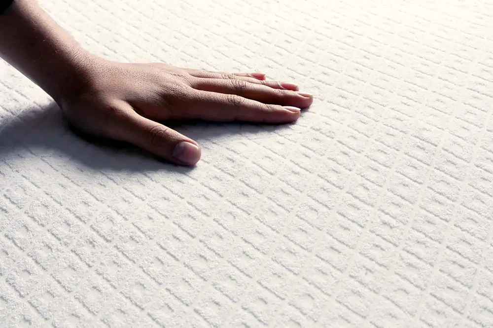 A hand pressing on a mattress
