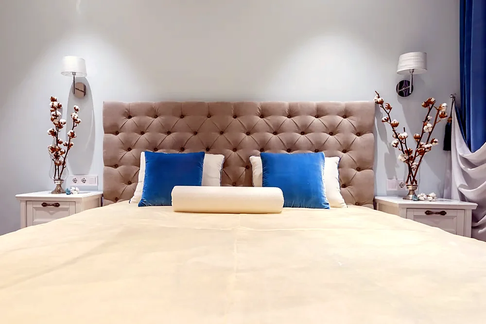 A bed with a tufted headboard and blue cushions
