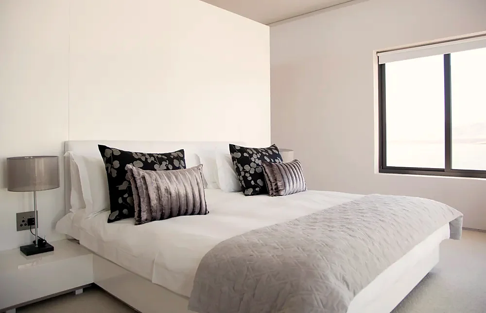 A bright bedroom with a made double bed
